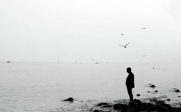 A Person Standing On Rocks By Still Water In Black And White - Art Print